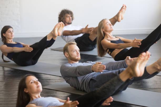Group of young sporty people in paripurna navasana pose picture id944619806